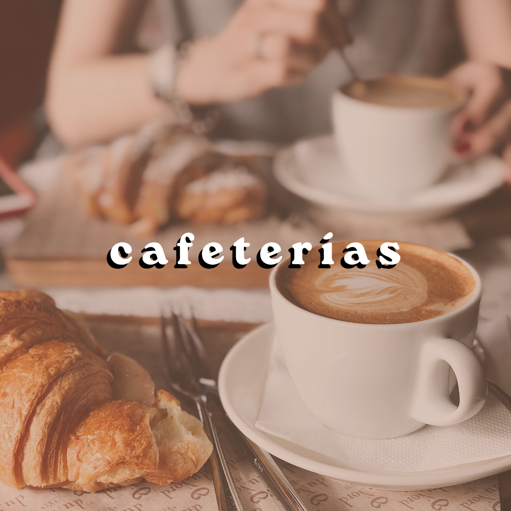 Taza de café acompañada de un croissant en una mesa de cafetería.